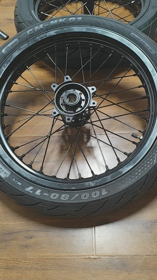 Black 17-inch Sur-Ron Ultra Bee supermoto wheels shown in the AMP Racing product video.